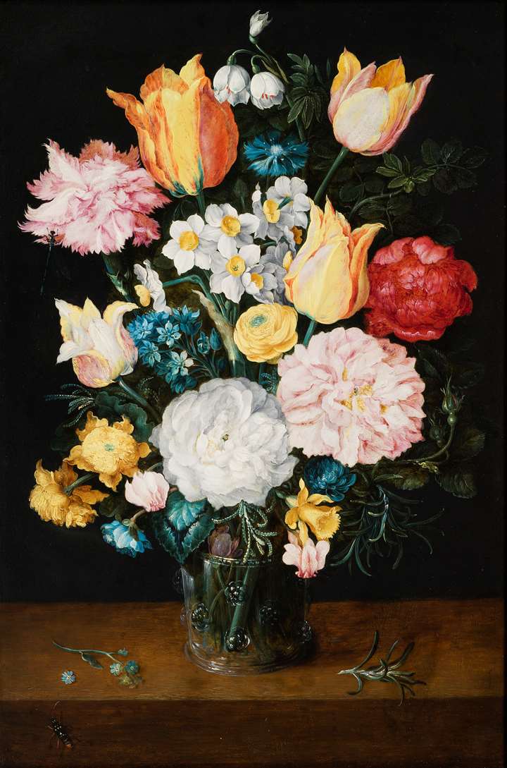 Still life of tulips, roses, narcissi and other flowers in a glass vase.